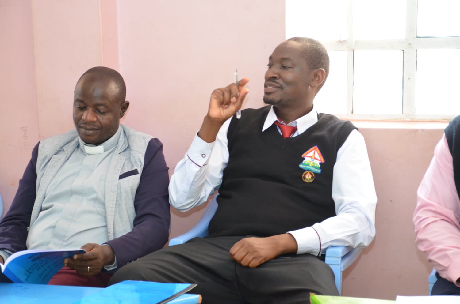 Maina in fellowship uniform at a Men&rsquo;s Fellowship meeting, papers on the table